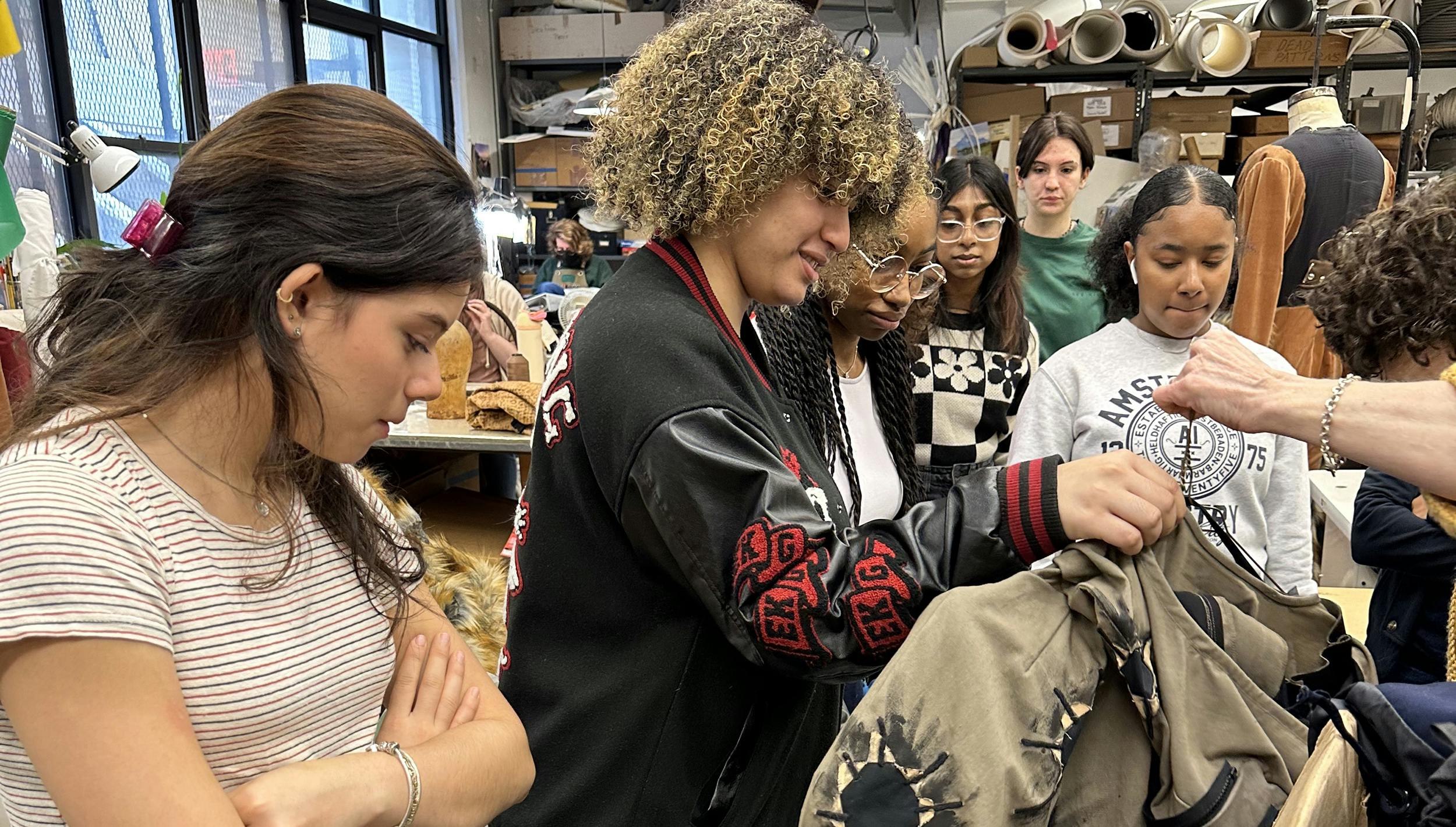 Open Stage Project students interact with a costume piece at a behind-the-scenes tour of Parsons-Meares, Ltd. costume shop.